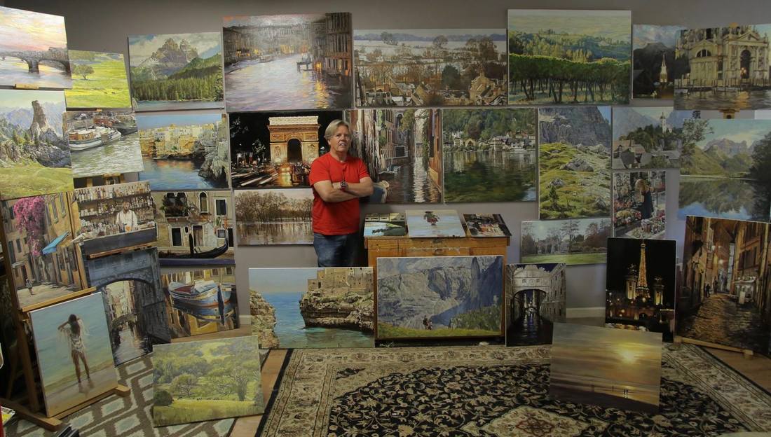 Photograph of Craig Nelson in studio surrounded by oil paintings