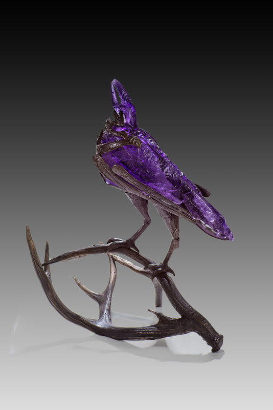 Glass and bronze sculpture of raven on antlers
